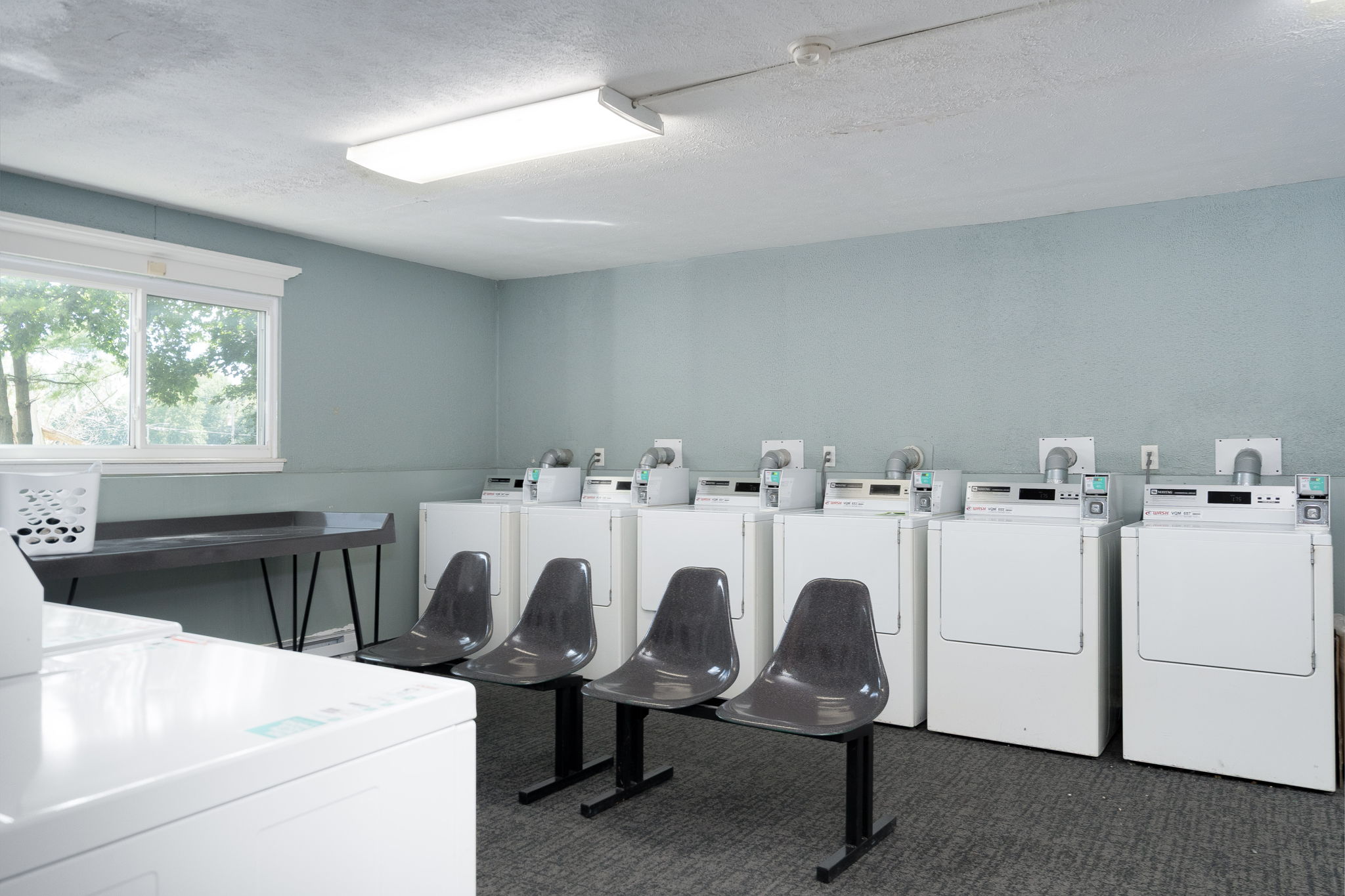 A laundromat with rows of washing machines and a table and chairs.